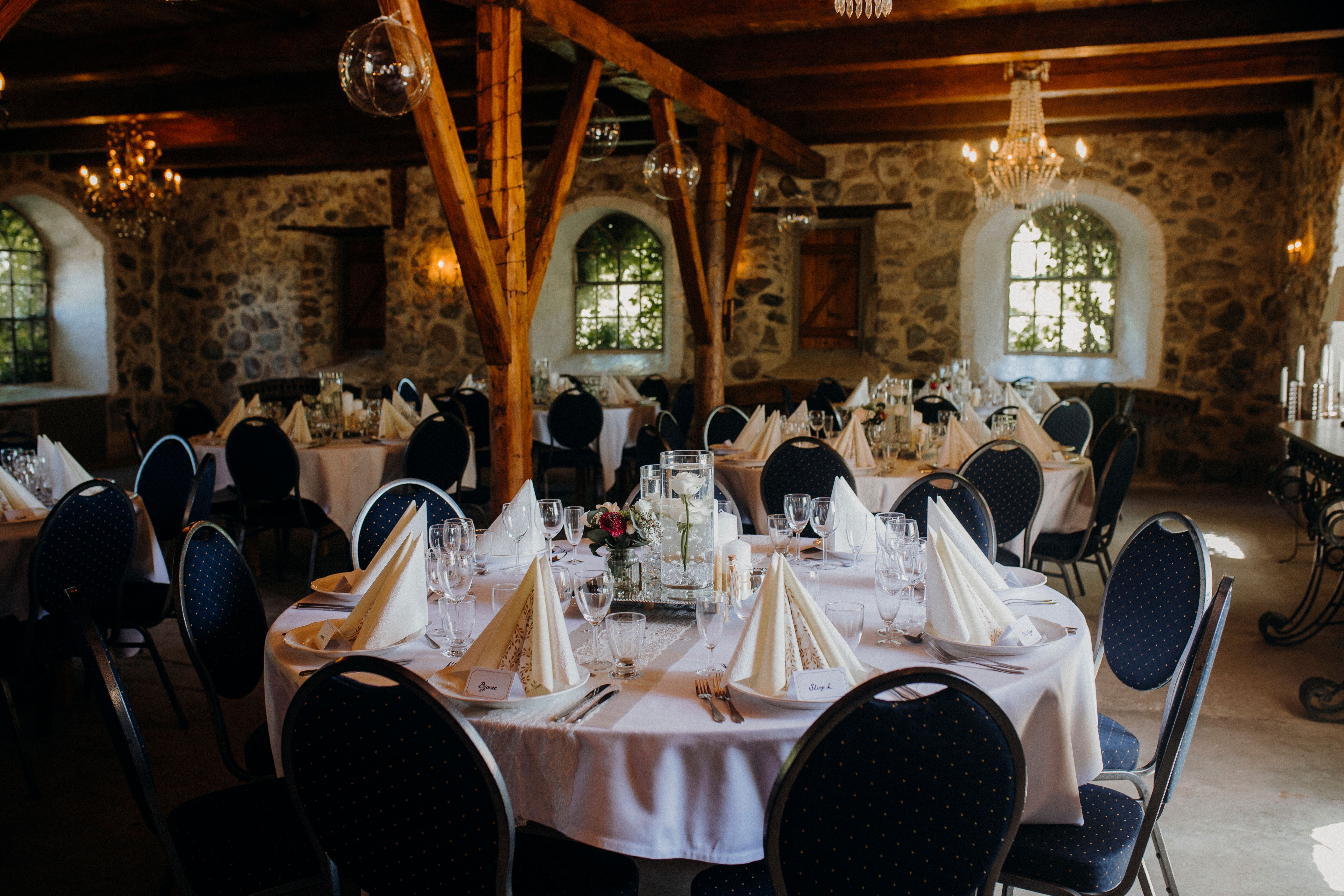 A beautifully decorated rustic restaurant dining room with round tables set for a fancy event.