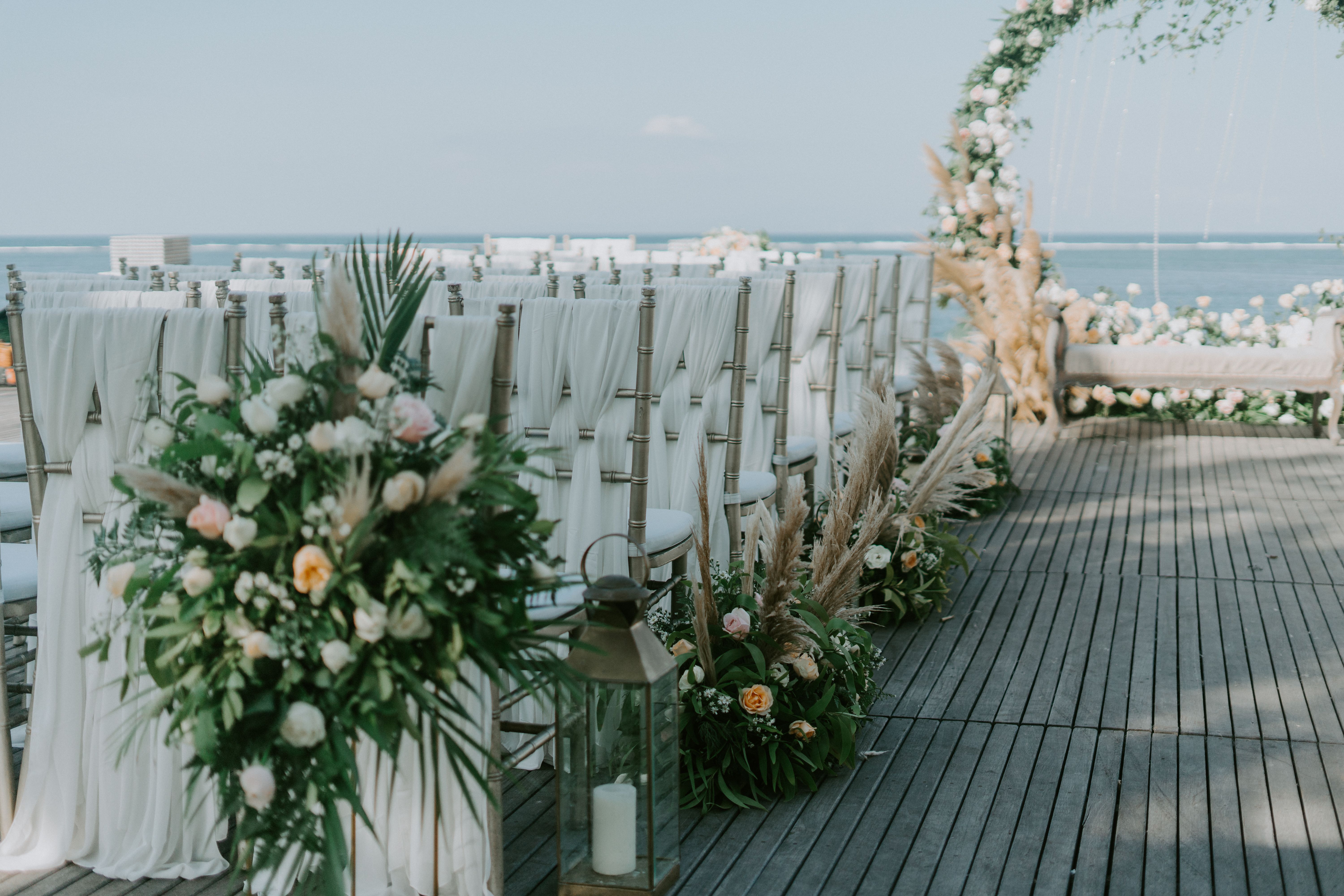 Upacara pernikahan luar ruangan yang elegan dengan bunga dan pemandangan laut. Ideal untuk acara romantis.