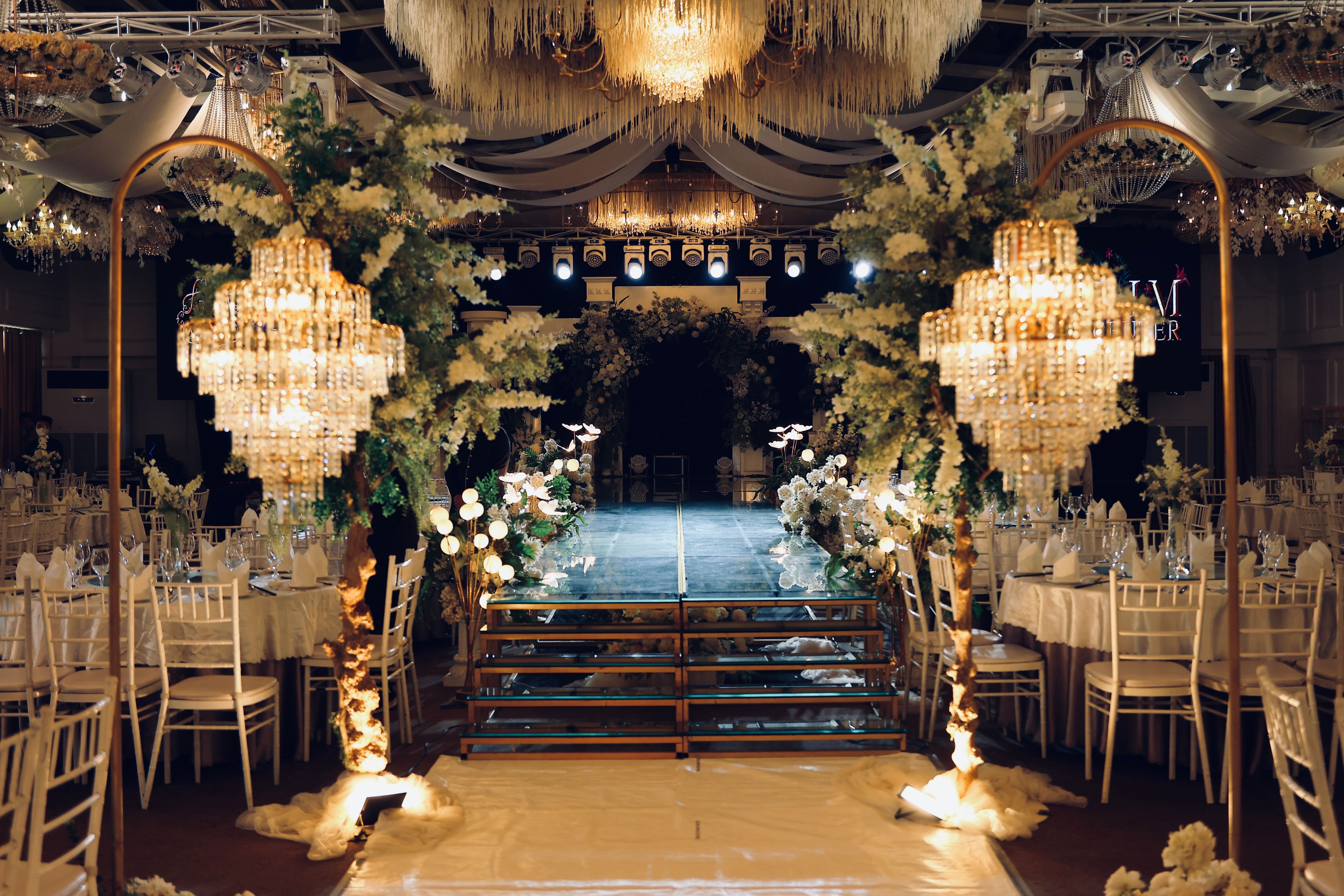 Luxurious wedding reception with ornate chandeliers, floral arrangements, and elegant table settings.