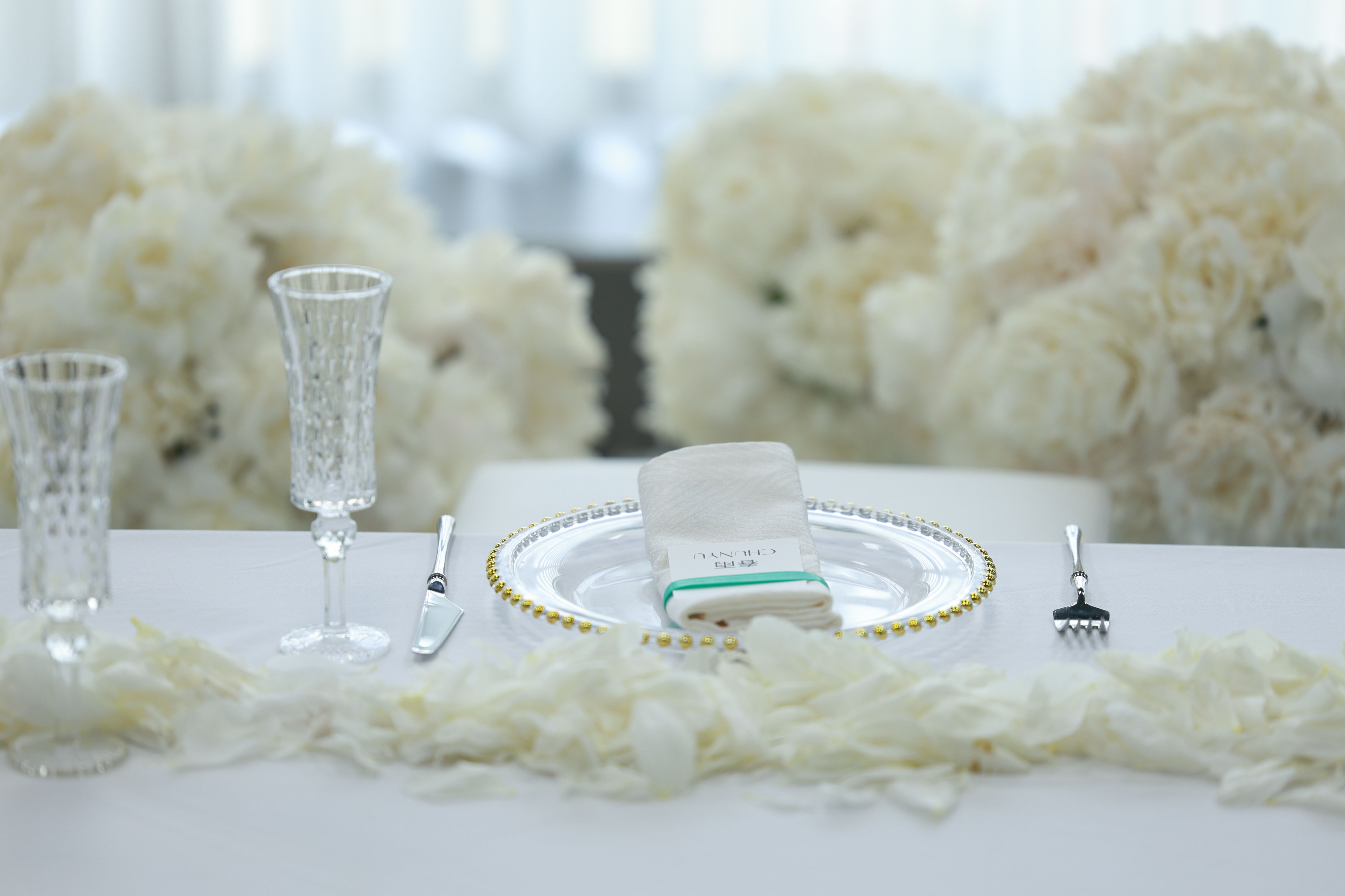 Elegant table setup with crystal glassware and white floral arrangement for a wedding.