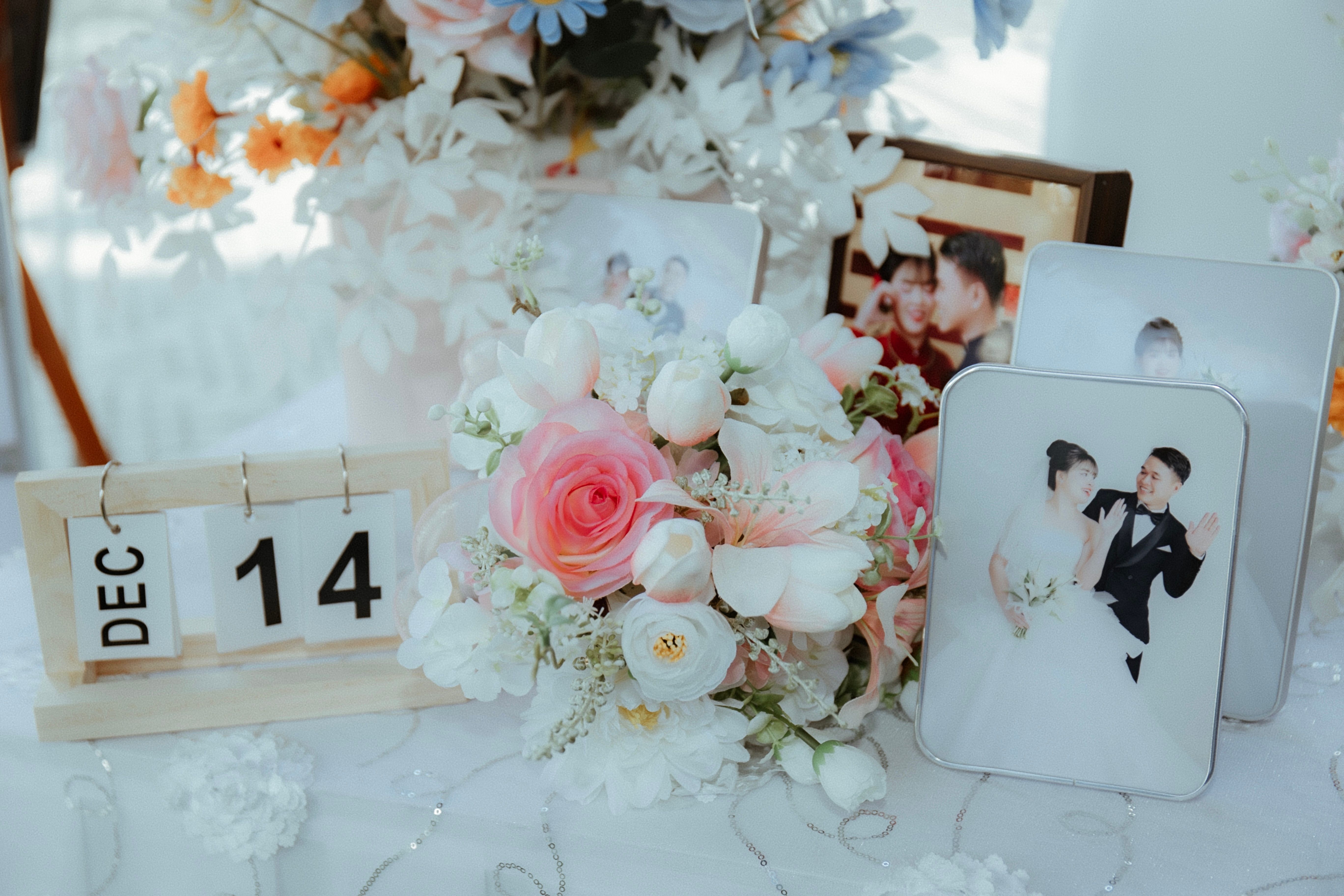 Beautiful wedding table setup with pink roses, photos, and a calendar highlighting December 14.