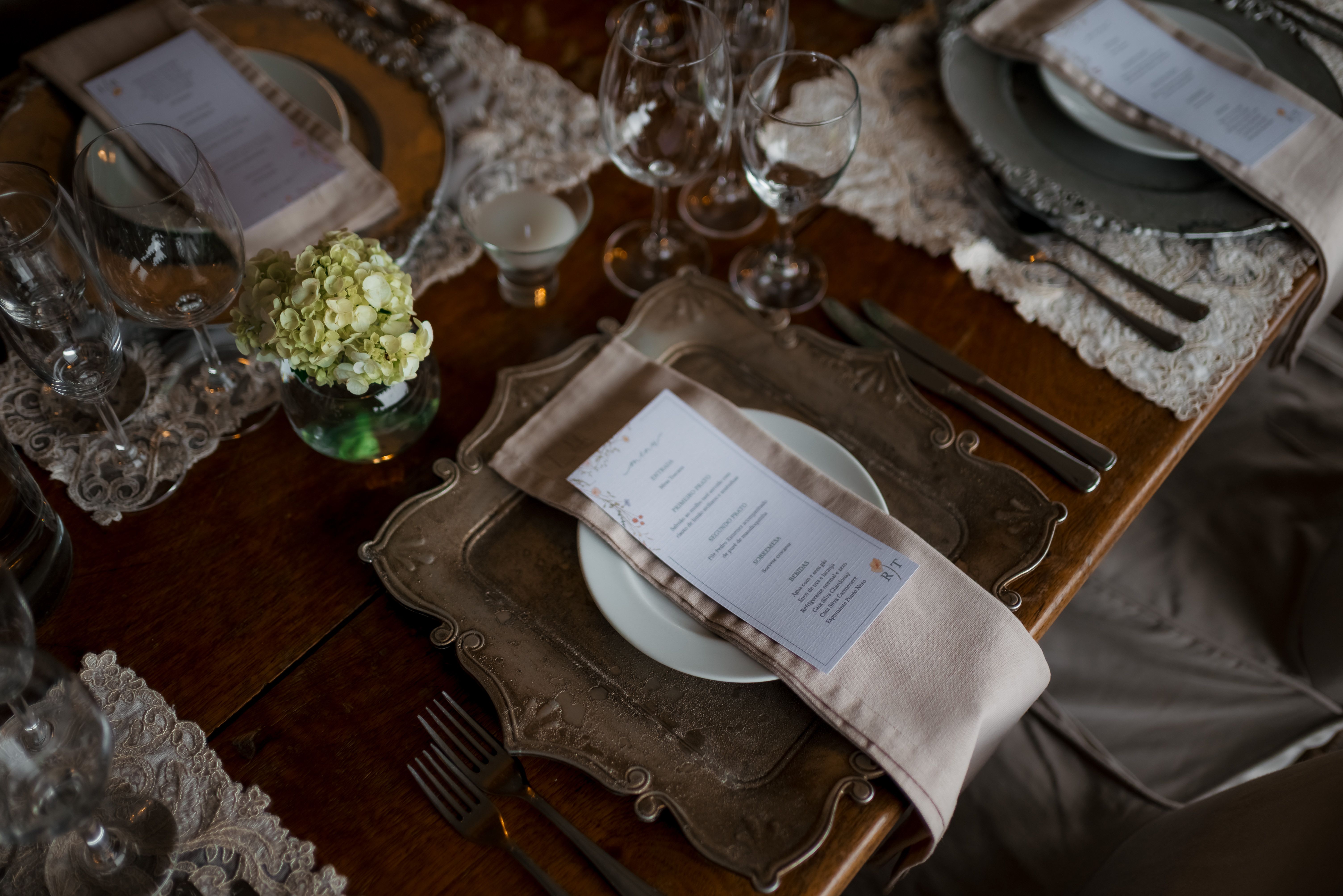 A beautifully arranged wedding table with decorative plates, glasses, menus, and floral centerpiece.