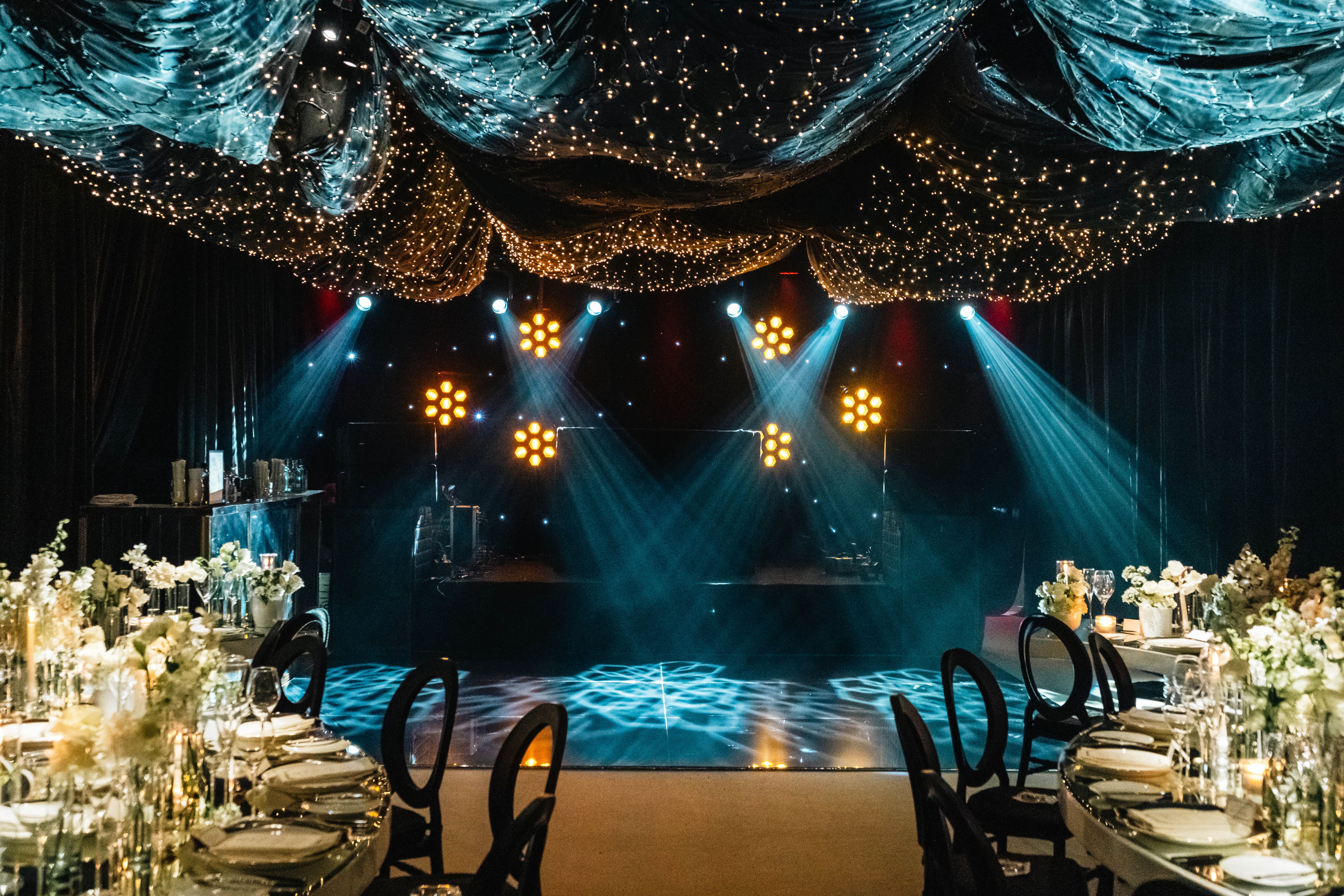 Luxurious event venue with shimmering lights and elegantly set tables, perfect for weddings or celebrations.