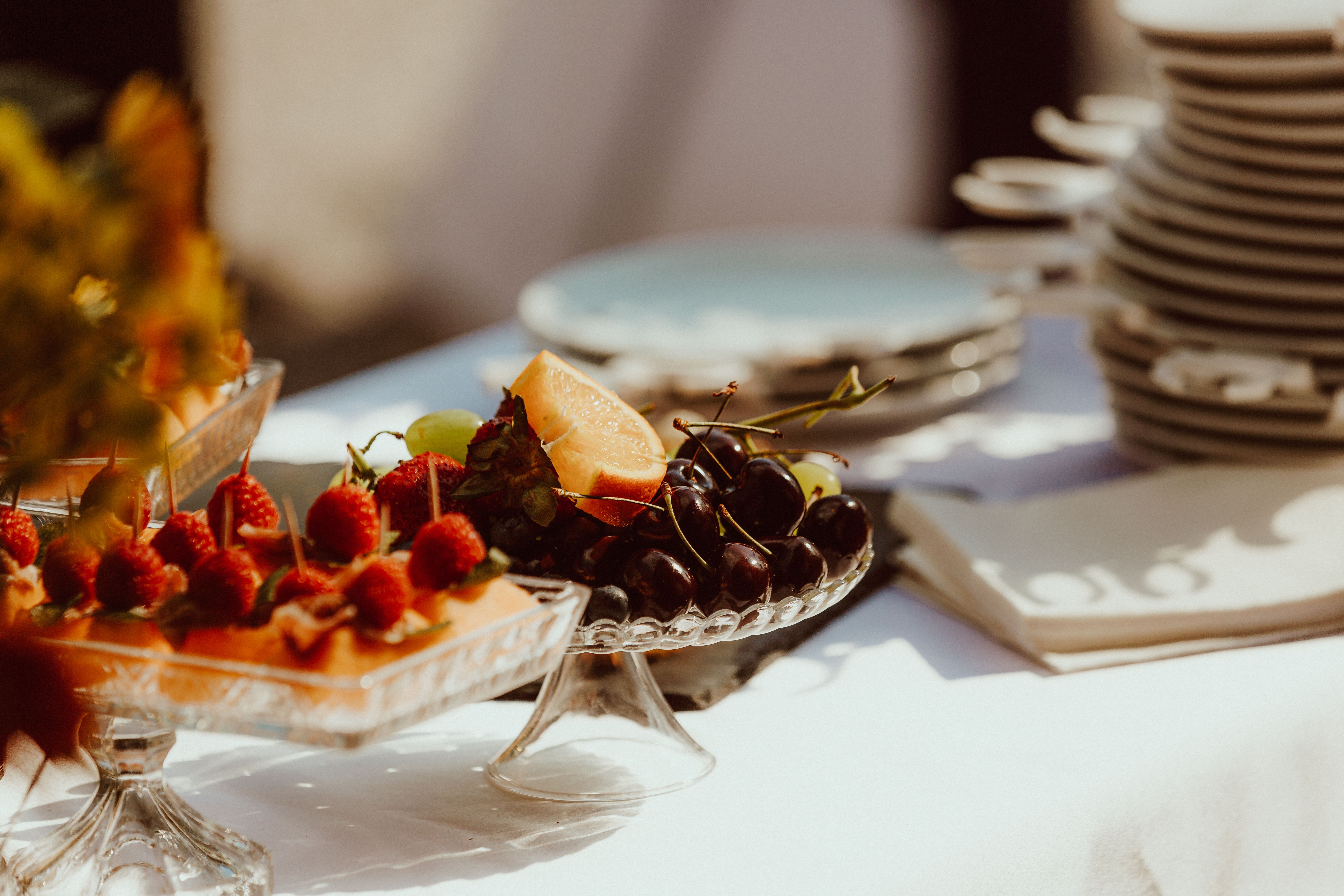 A beautifully arranged fruit tray featuring cherries, grapes, and melon on a sunny day.