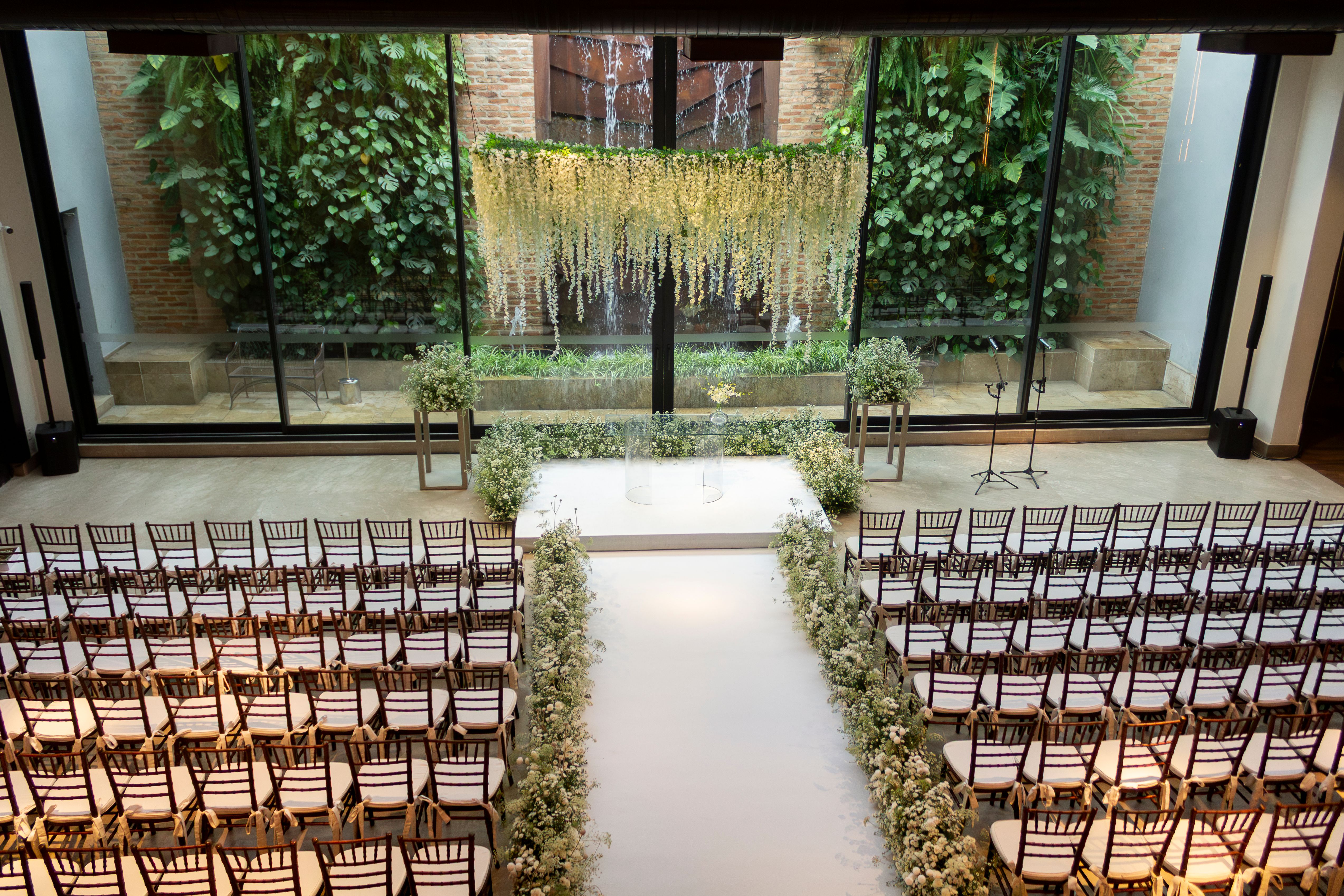 Tempat pernikahan dalam ruangan dengan dekorasi bunga putih elegan dan pengaturan tempat duduk di São Paulo.