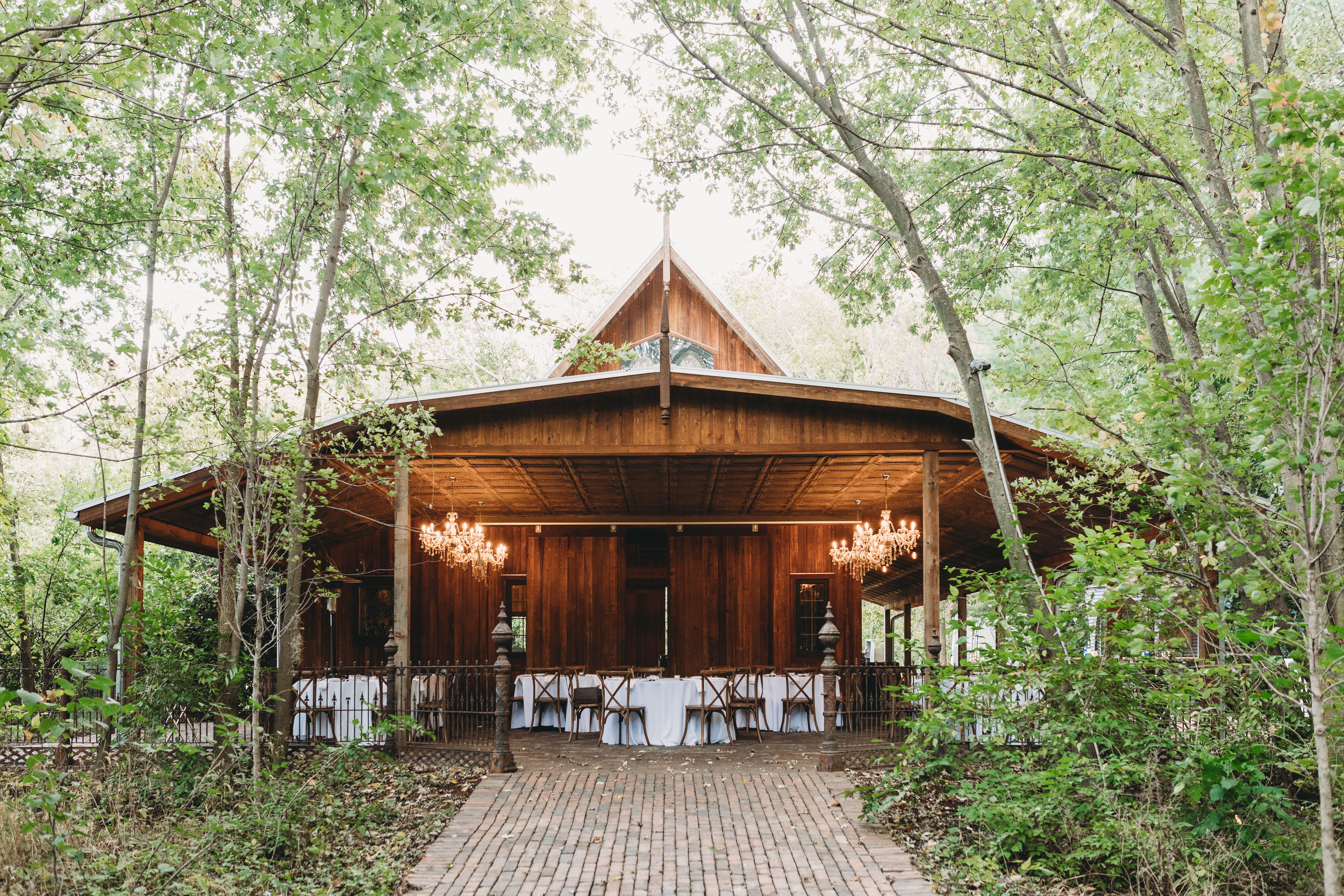 Charming wooden building with chandeliers, set in a lush forest, perfect for events.