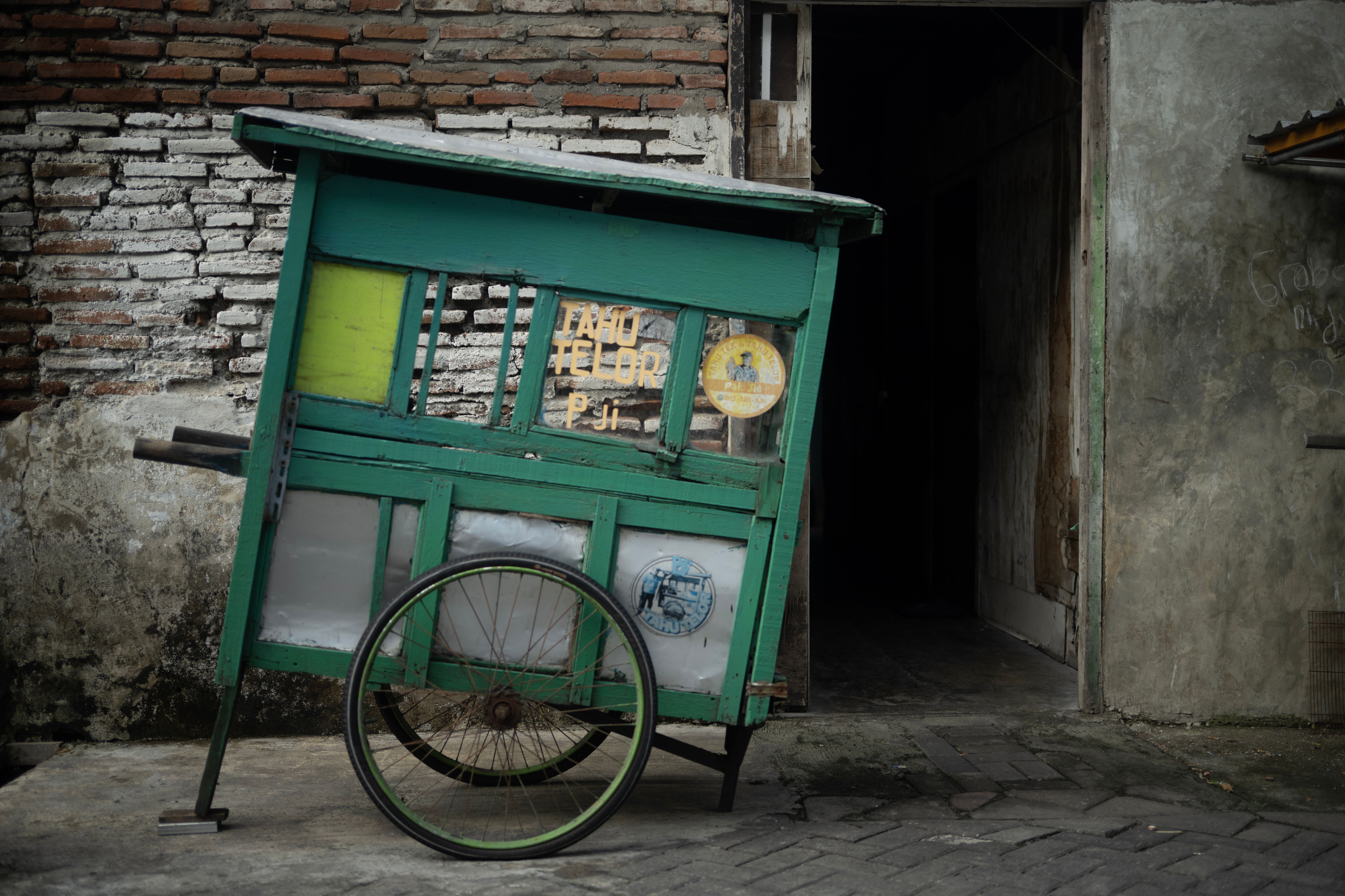 A rustic food cart with a weathered charm stands against an old brick wall, showcasing local street food culture.