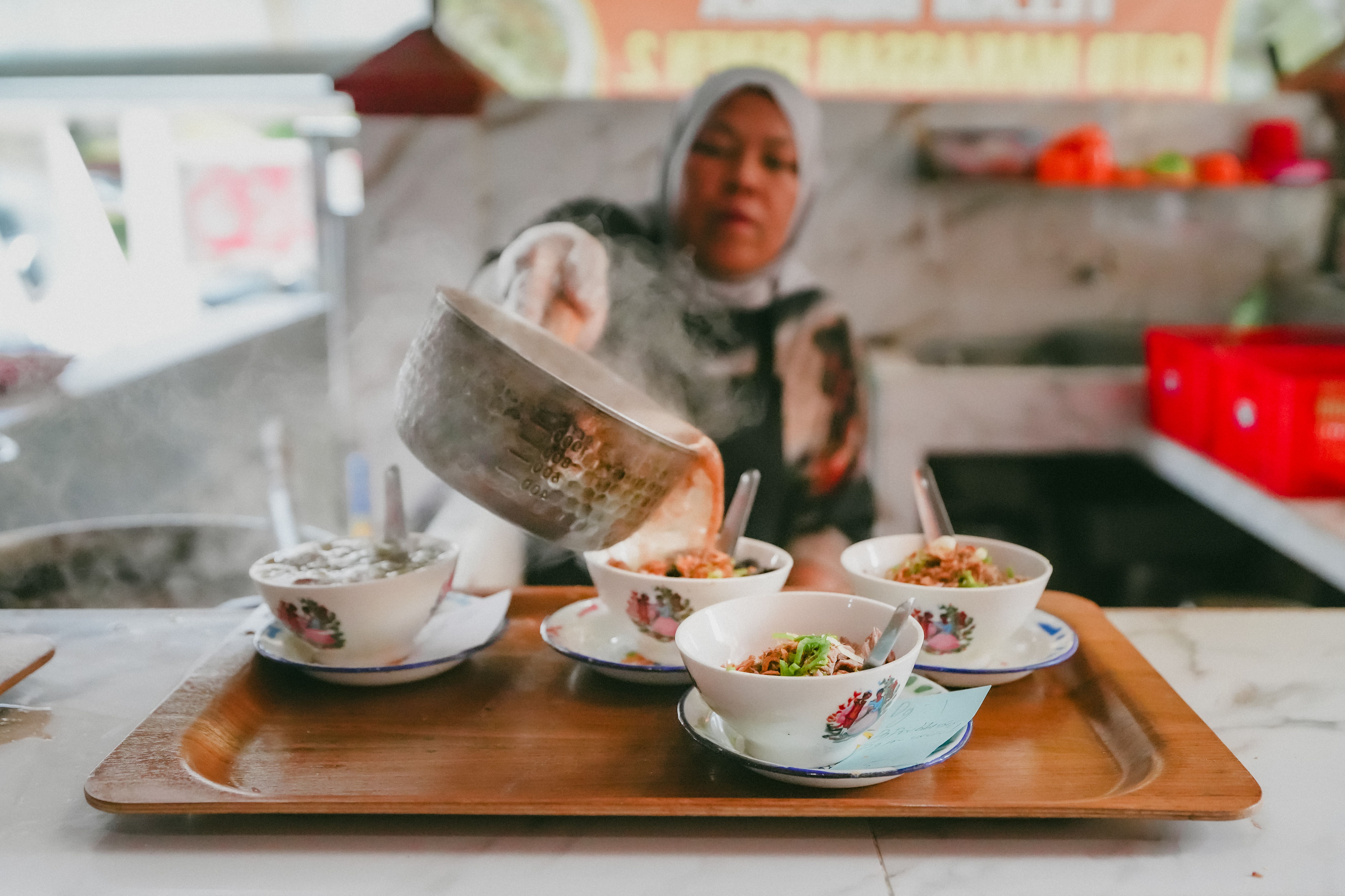 Chef prepares traditional Coto Makassar at a street food stall in Indonesia.
