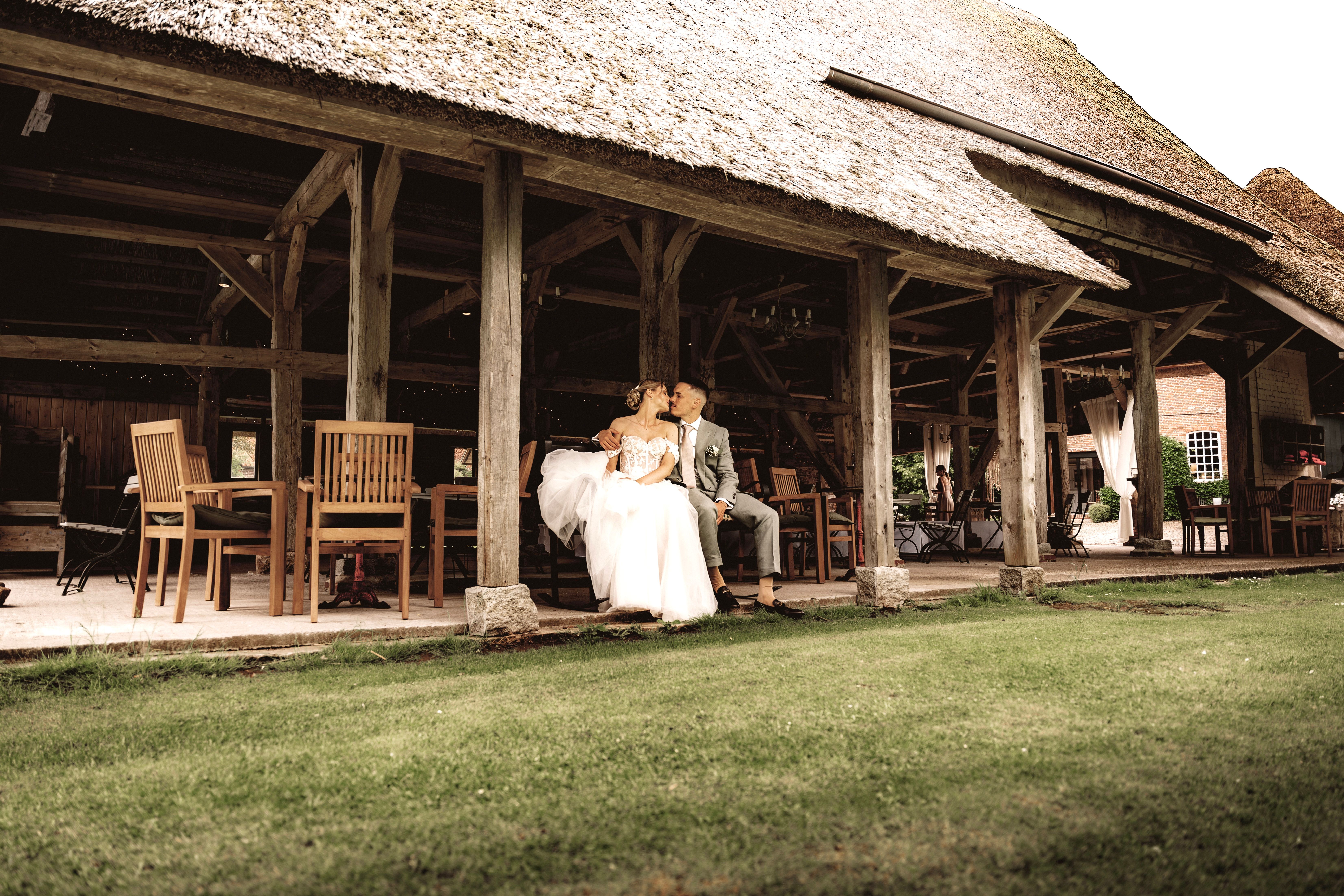 Bride and groom sitting lovingly under a rustic barn setting on their wedding day.