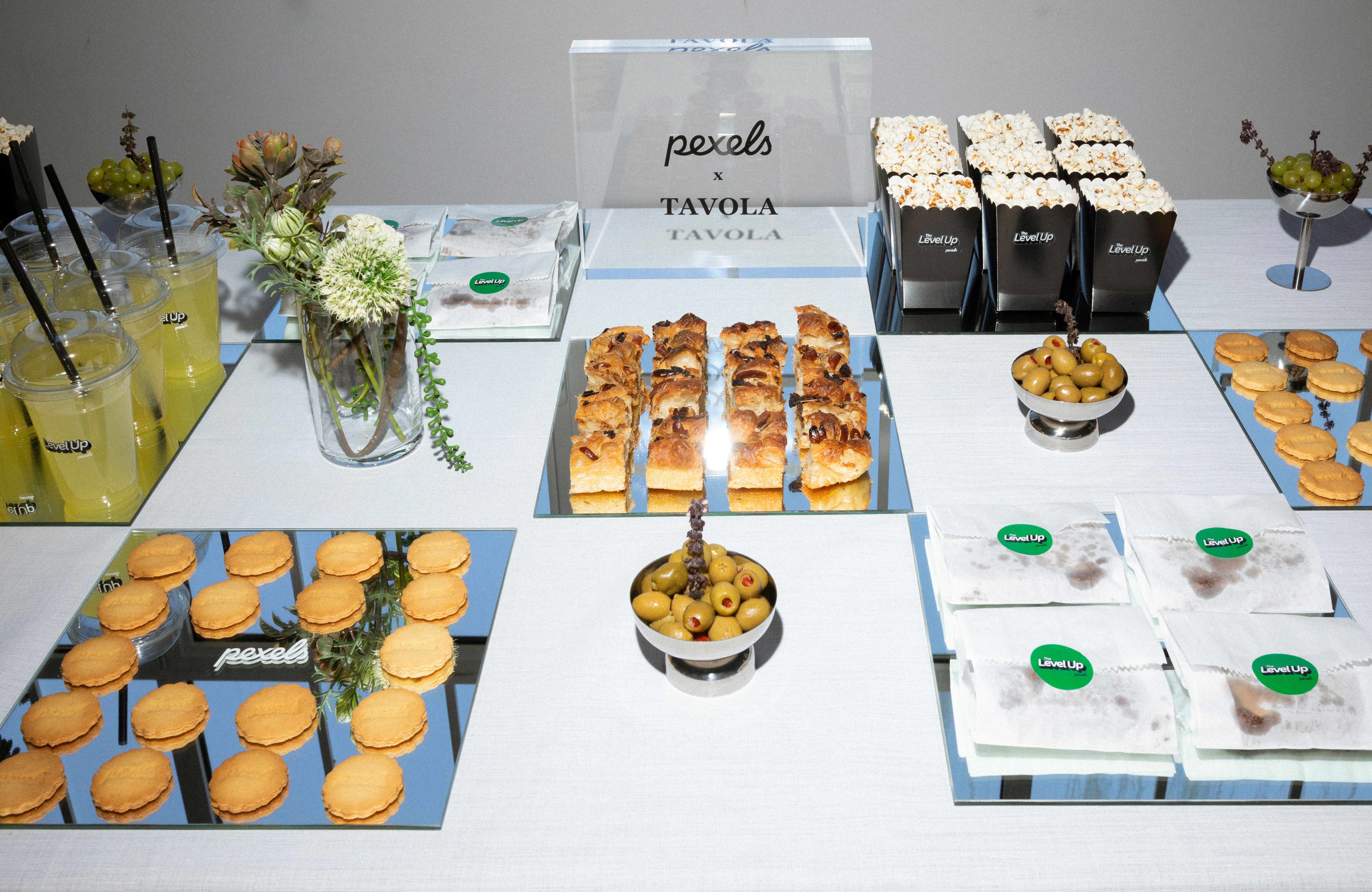 Stylish snack table featuring pastries, popcorn, olives, and drinks at an event.