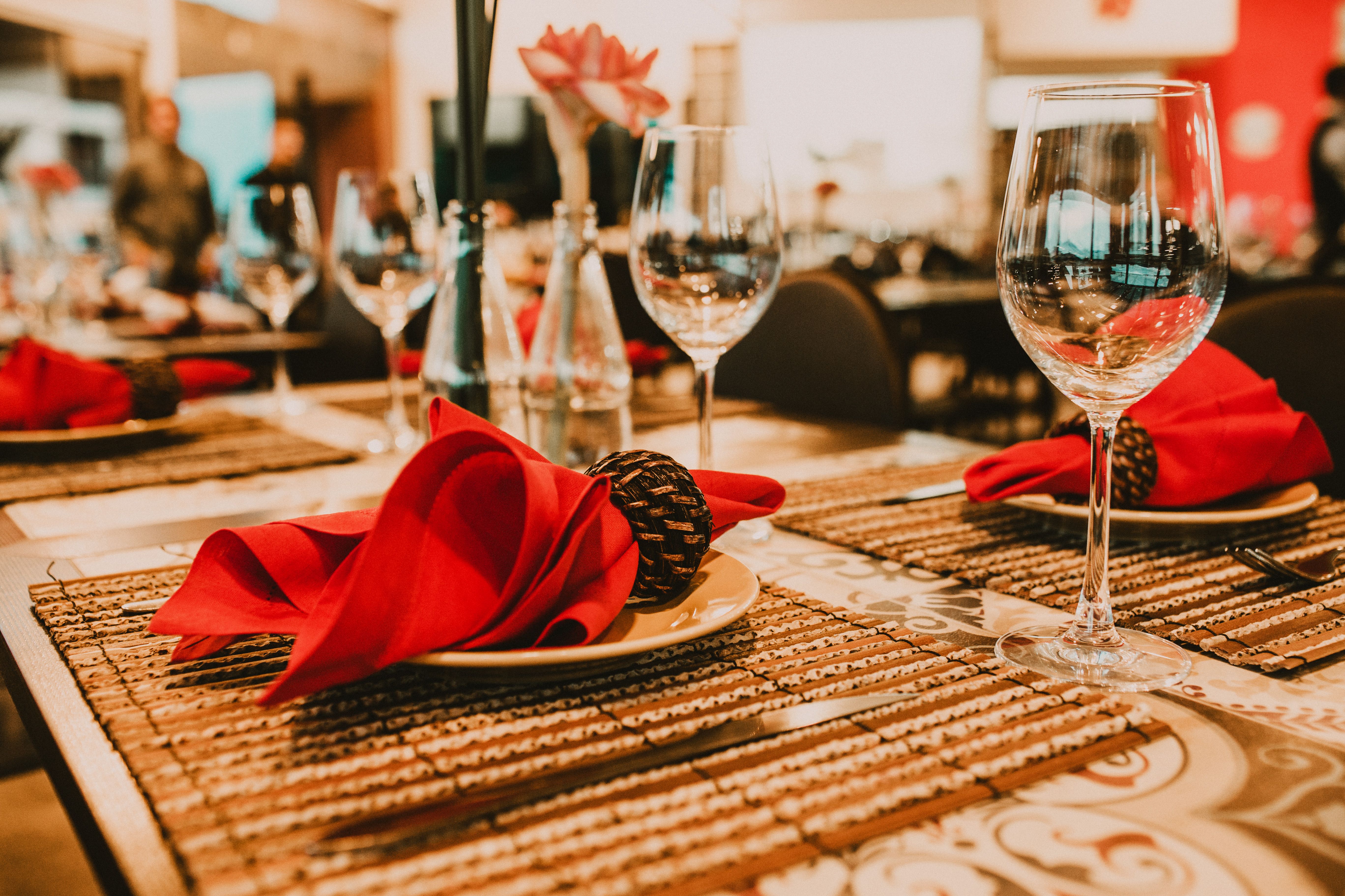 Set table with wineglasses and red napkins placed on plates in spacious banquet hall