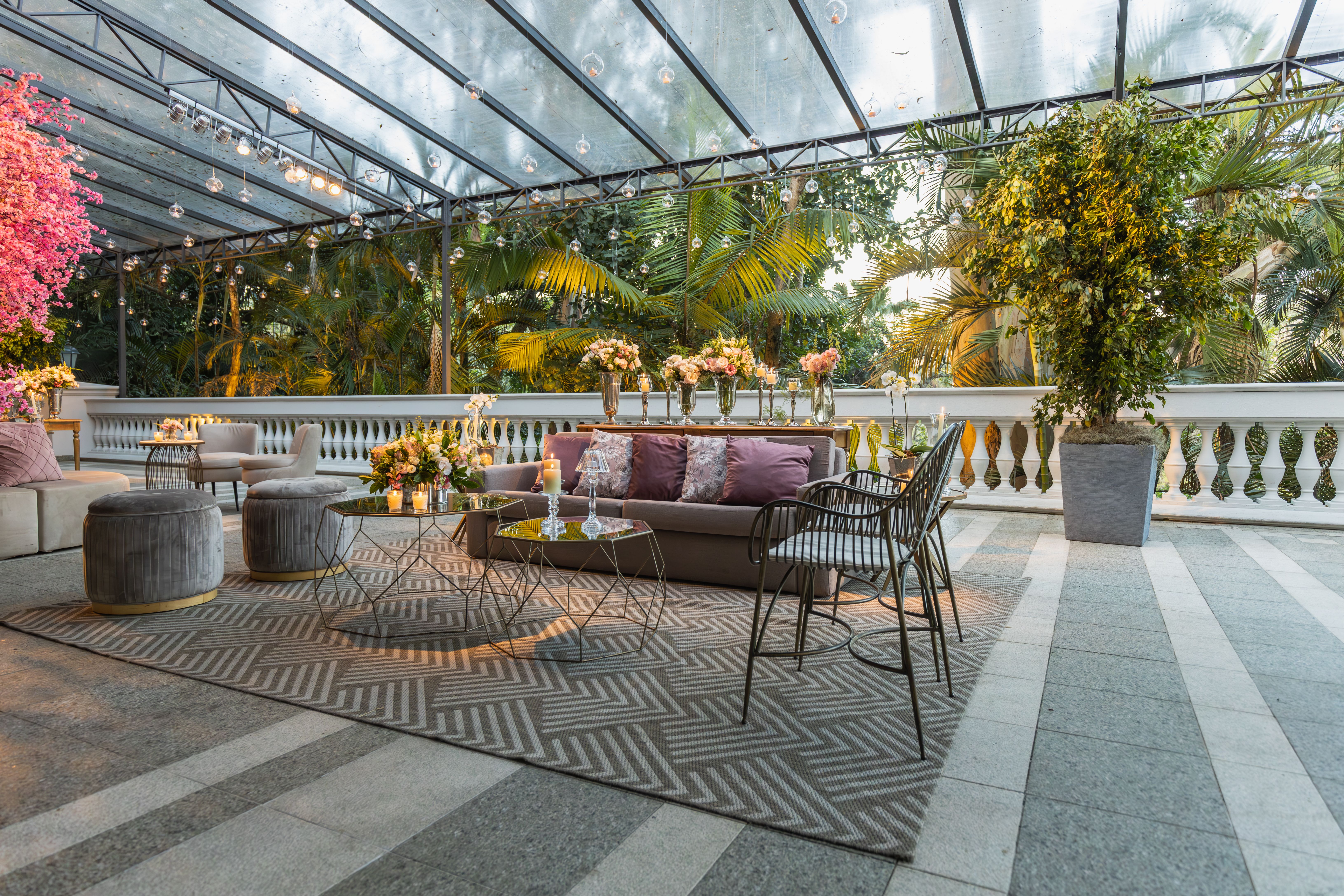 Stylish lounge area in a greenhouse setting featuring elegant furniture and lush greenery.