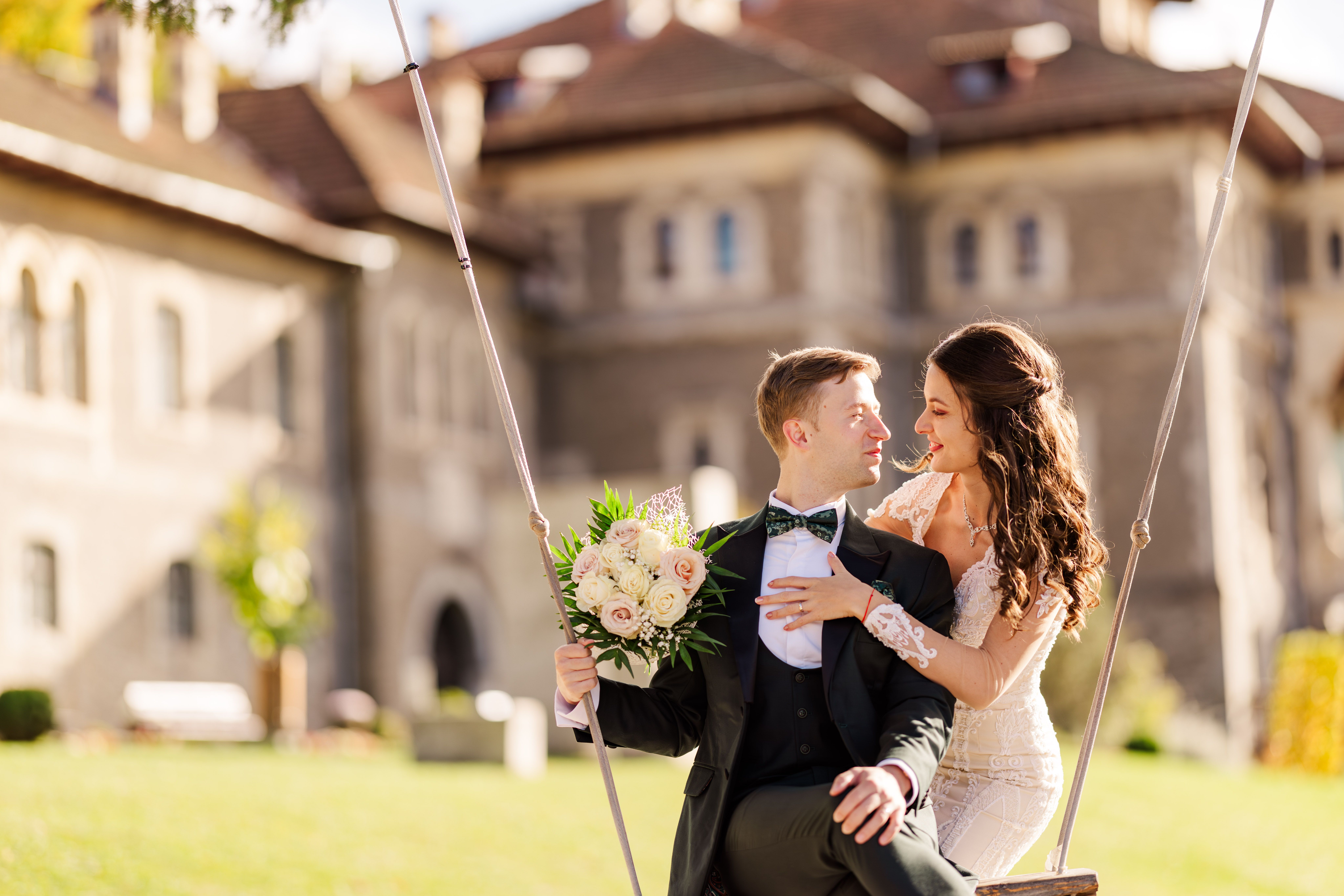 A newlywed couple enjoying a moment on a swing in a picturesque Romanian setting, capturing love and joy.