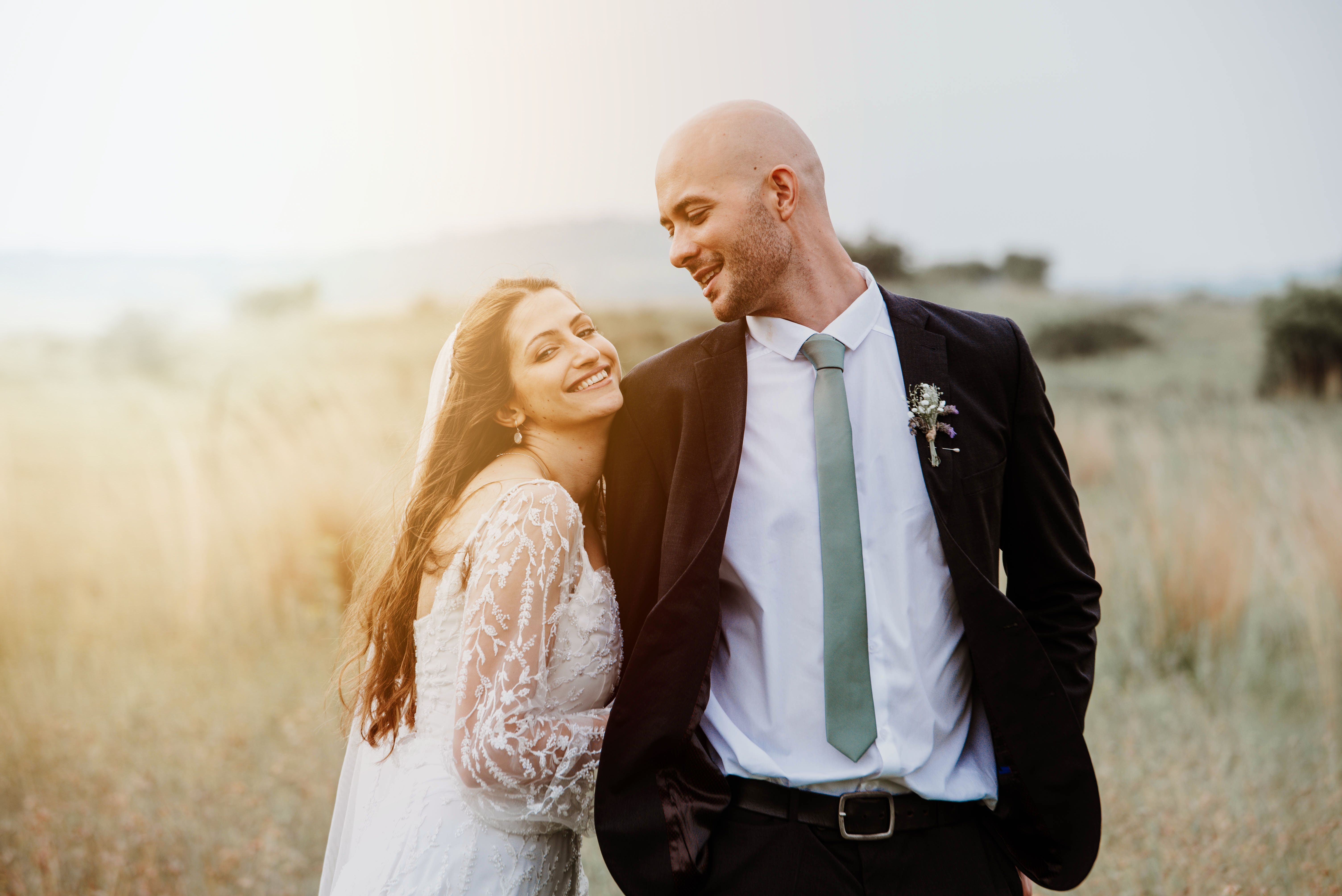 A happy couple is captured sharing a moment of joy in a serene, sunlit meadow.