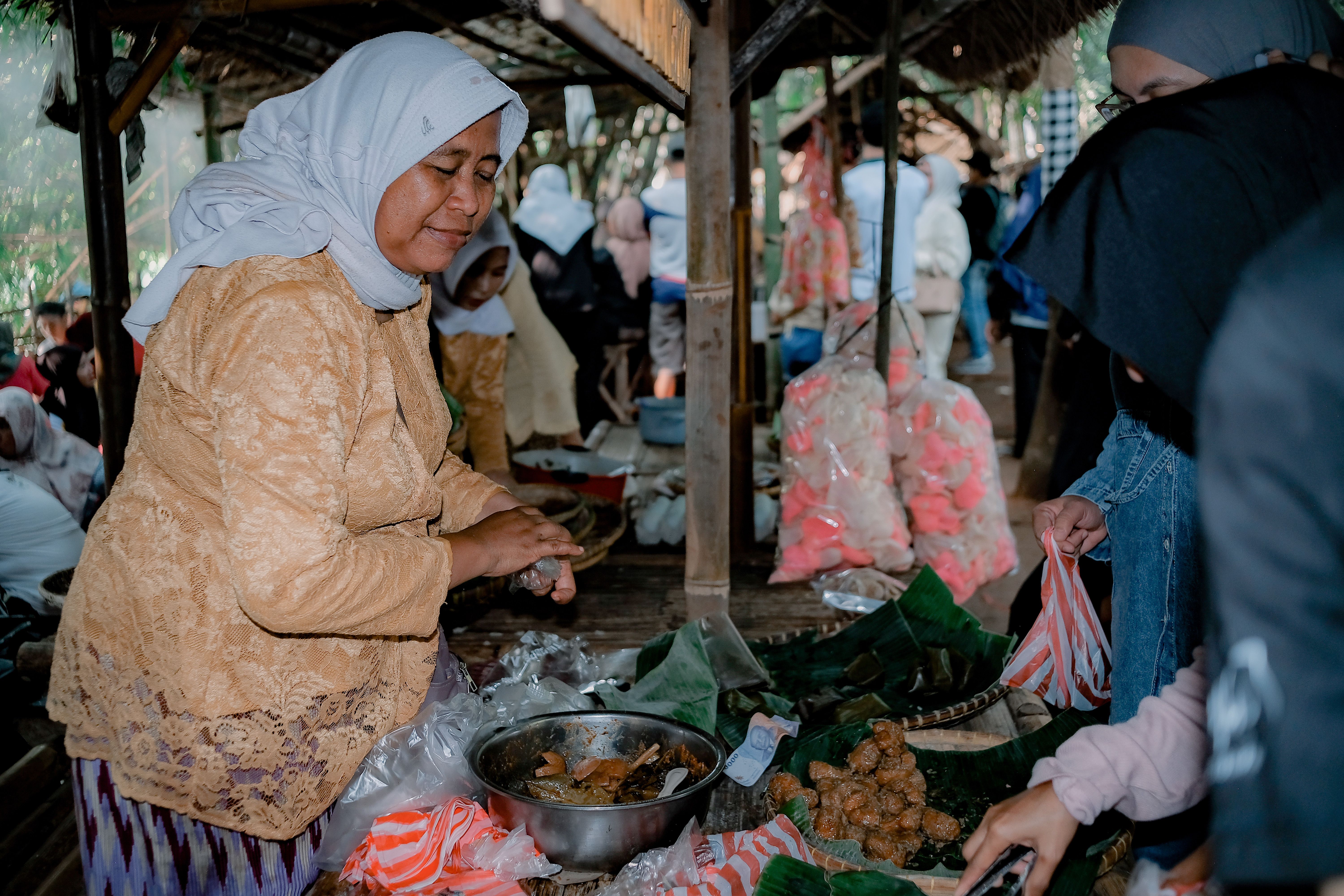 Vendor at a bustling street food market in West Java, Indonesia, serving traditional dishes.