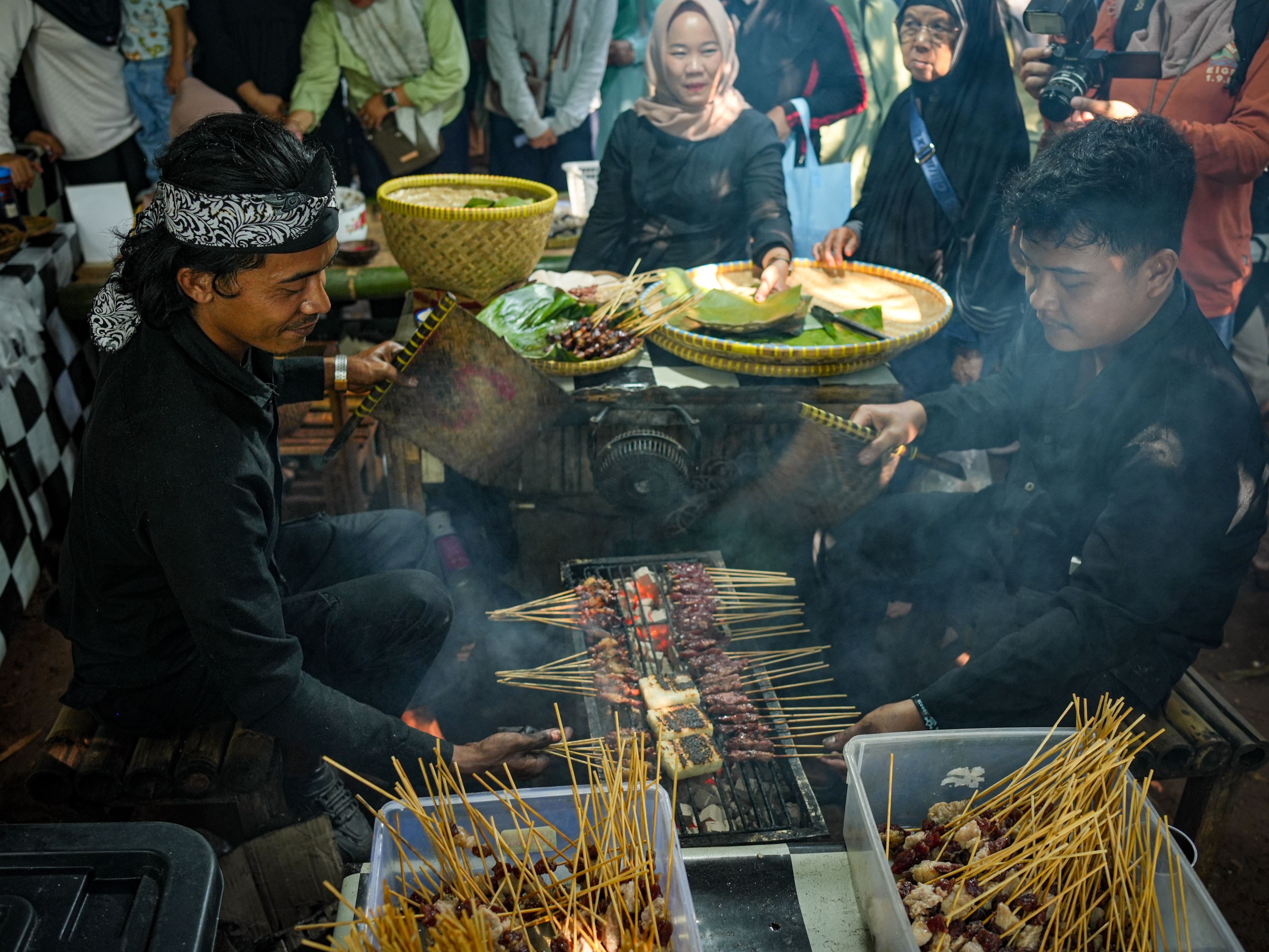 Men grilling satay skewers at a traditional Indonesian market in Purwakarta. Authentic culinary experience.