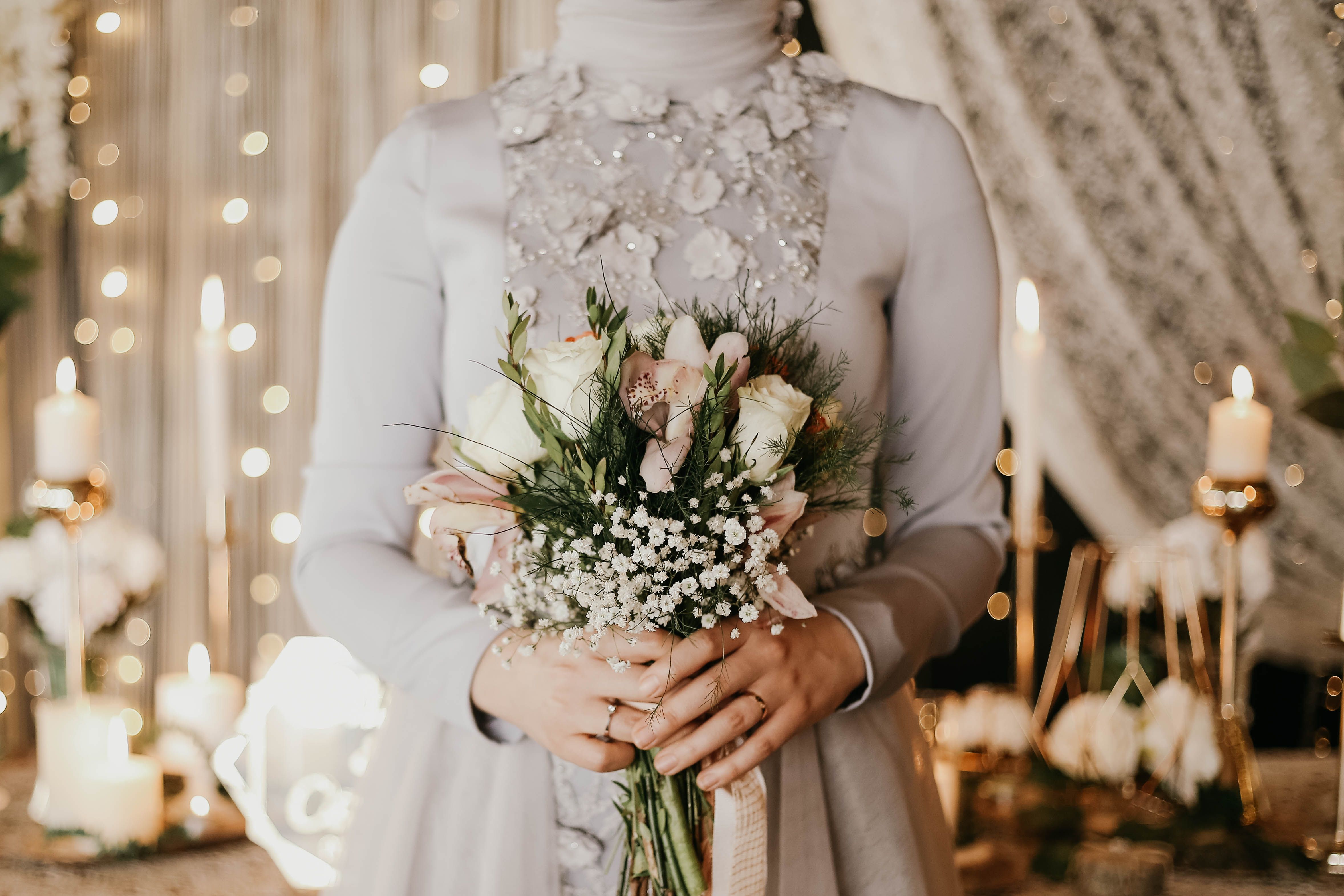 A bride holds a delicate bouquet during an elegant wedding ceremony, adorned with candles and floral decor.